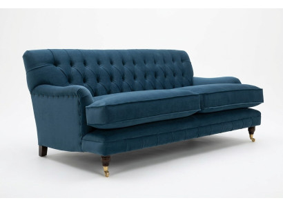 Zils mūsdienīgs Chesterfield trijosvietu luksusa dīvāns dzīvojamās istabas gultā.